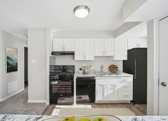A modern kitchen with white cabinets and black appliances.