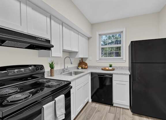 Modern kitchen with white cabinetry and black appliances at Highland Ridge Apartments, Maryland