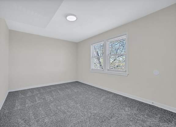 Empty bedroom with gray carpet and window blinds at Highland Ridge Apartments, Capitol Heights, MD 20743