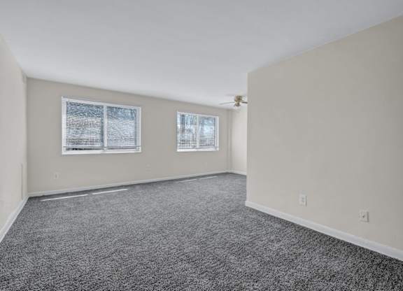 Empty carpeted living room with two windows at Highland Ridge Apartments, Capitol Heights