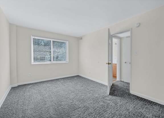 Empty bedroom with gray carpet and closet at Highland Ridge Apartments, Maryland
