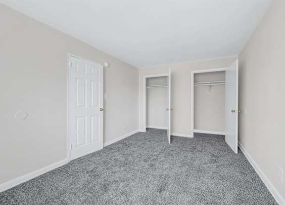 Empty bedroom with dual closets and carpet at Highland Ridge Apartments, Maryland, 20743