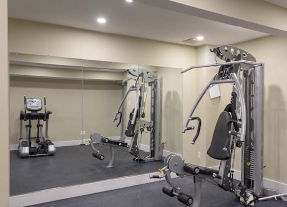 A gym with a variety of equipment including a leg press machine, a chest press machine, and a leg curl machine.