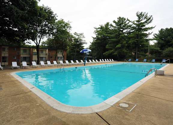 A large swimming pool surrounded by trees and chairs.