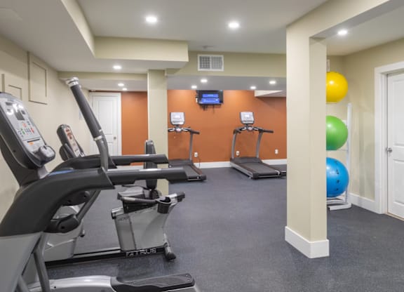 A gym with a treadmill, exercise bike, and elliptical trainer.