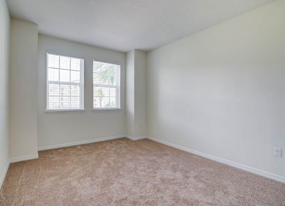 a bedroom with two windows and a carpeted floor  at Century Avenues, Lakeland, FL