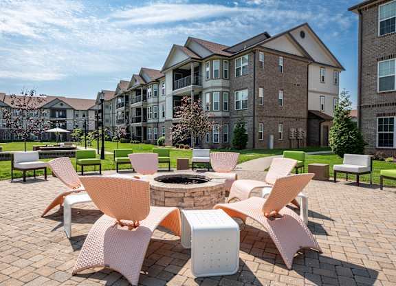 an outdoor lounge area with chairs and a fire pit at the enclave at woodbridge apartments in at Century Belmont Station, Louisville, KY