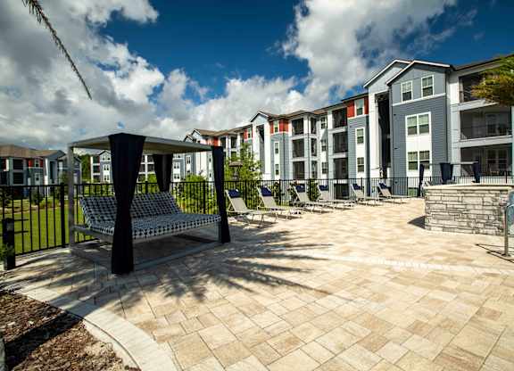 a courtyard with benches and a pool in front of an apartment building at Century Dunes Apartments, Deland, FL, 32724