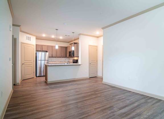 a living room and kitchen with white walls and wood floors  at Century New Holland, Gainesville