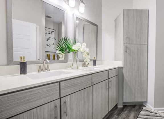 a bathroom with gray cabinets and white countertops at Century University City, Charlotte, North Carolina