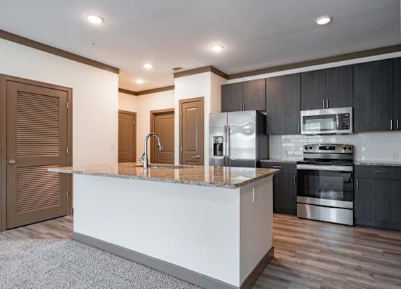 A modern kitchen with a white island and stainless steel appliances. at Century Belmont Station, Louisville, 40243