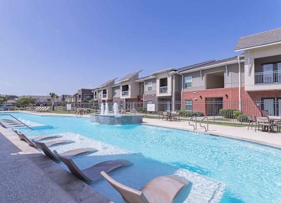 our apartments offer a swimming pool with chairs and a fountain at Century Palm Bluff, Portland, TX, 78374