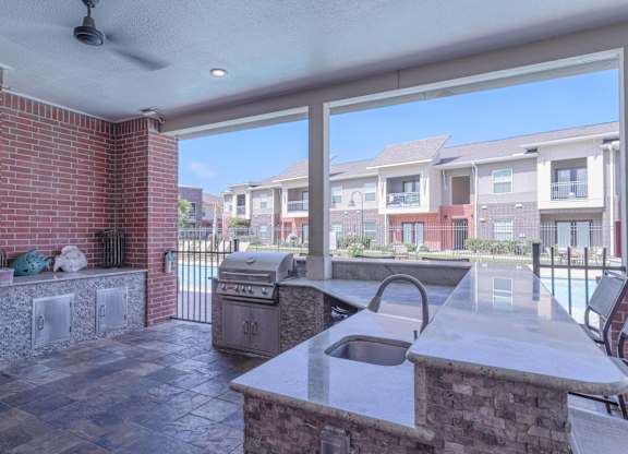 an outdoor kitchen with a grill and a large window at Century Palm Bluff, Portland, Texas