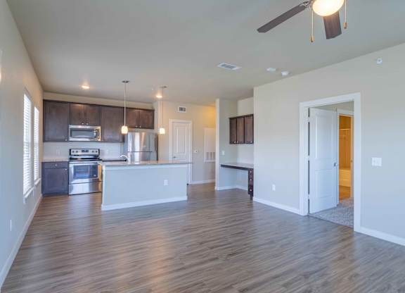 an empty living room with a kitchen and a ceiling fan at Century Palm Bluff, Portland, Texas