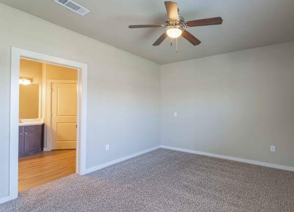 a bedroom with a ceiling fan and a door to a bathroom at Century Palm Bluff, Portland, 78374