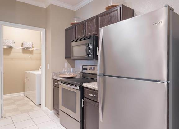 a kitchen with stainless steel appliances and black cabinets at Century South Shore, League City, Texas