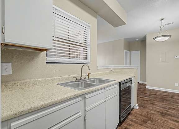 A kitchen with a sink, dishwasher, and a window with blinds.