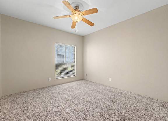 A room with a ceiling fan and a window with blinds.