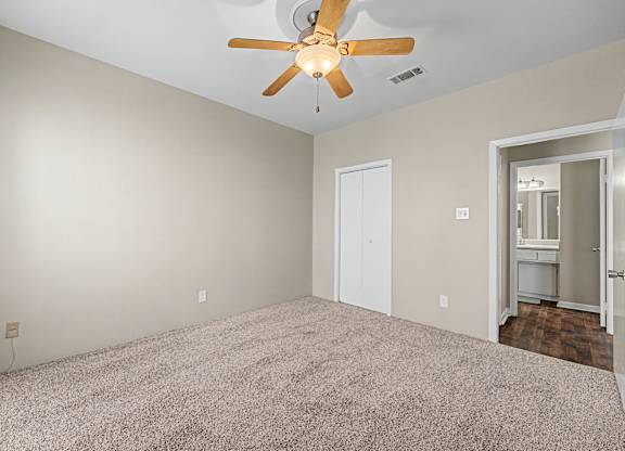 A room with a ceiling fan and carpeted floor.