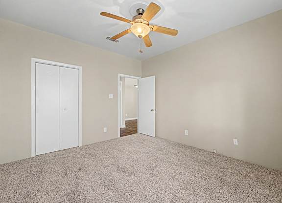 A room with a ceiling fan and carpeted floor.