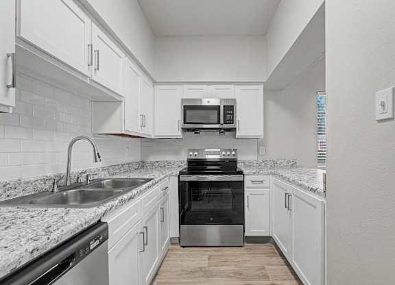 A modern kitchen with white cabinets and a granite countertop.