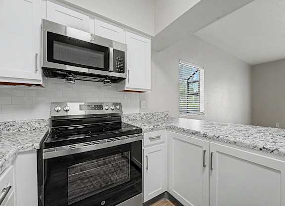 A kitchen with a black oven and microwave above a granite countertop.