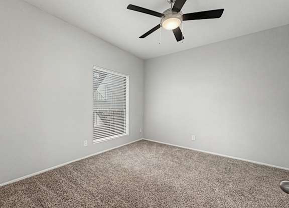 A room with a ceiling fan and carpeted floor.