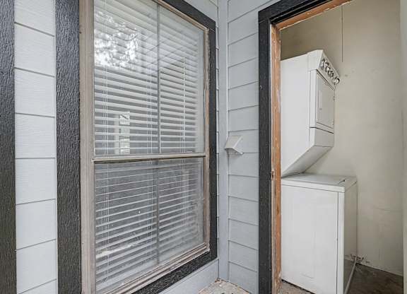 A white window with blinds and a white air conditioner unit in a room.