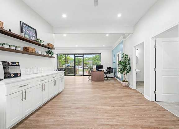 A kitchen with white cabinets and a wooden floor.