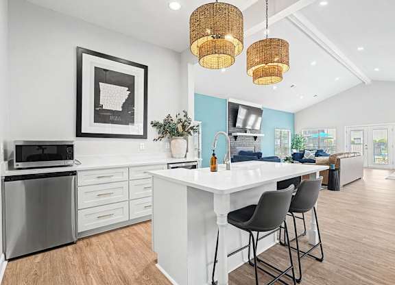 A kitchen with a white island and grey chairs.