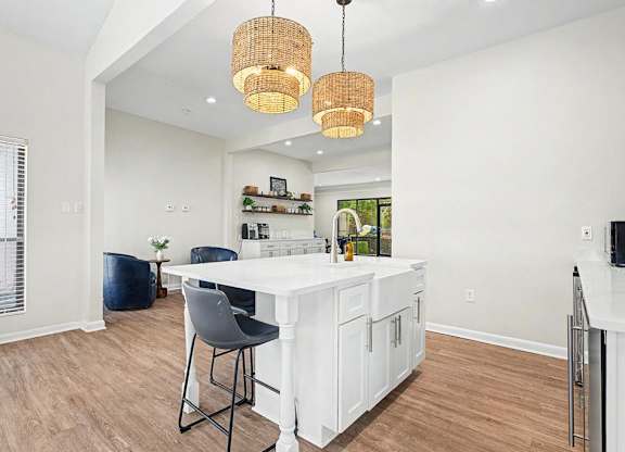 A kitchen with white cabinets and a bar area with a white countertop.