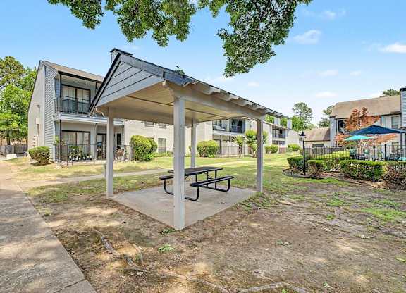 A covered picnic table is in the foreground of a residential area.