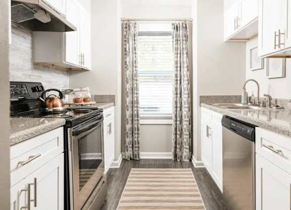 a kitchen with stainless steel appliances and white cabinets at The Sapphire, Decatur, Georgia