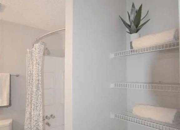 a white bathroom with a shower and a toilet at The Sapphire, Decatur, 30035