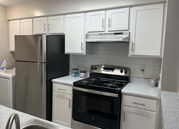 a kitchen with white cabinets and stainless steel appliances at The Hub at 934 Apartments, Georgia, 30349