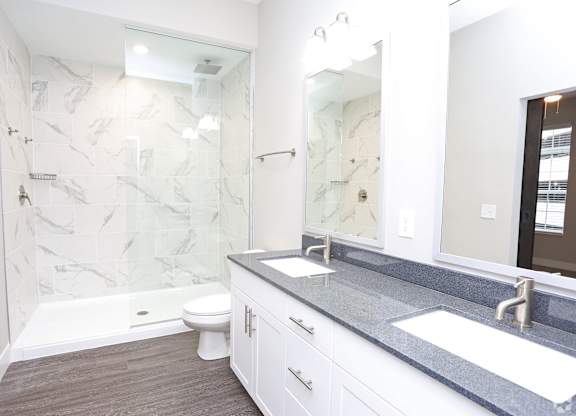 a bathroom with a shower and a sink and a mirror at Century Baxter Avenue, Louisville, KY 40204