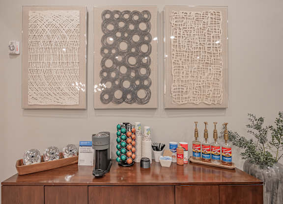 three pieces of artwork hanging on the wall above a counter with coffee and other items at Century HomePlace, Prattville, 36066