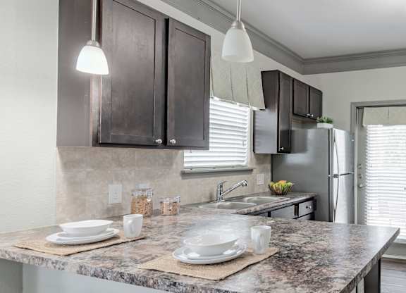 a kitchen with a marble counter top and a stainless steel refrigerator at Century HomePlace, Prattville, AL