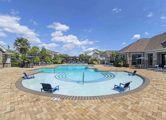a large swimming pool with chairs around it in front of a house at Century HomePlace, Prattville Alabama