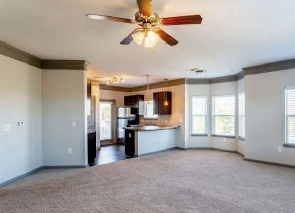 an empty living room with a ceiling fan and a kitchen at Century HomePlace, Prattville Alabama