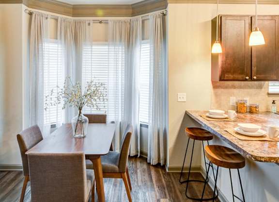 a dining room with a table and chairs and a kitchen with windows at Century HomePlace, Alabama