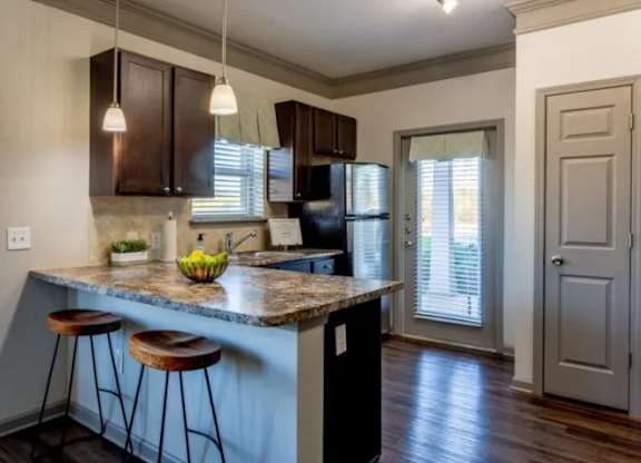 a kitchen with an island with stools and a refrigerator at Century HomePlace, Prattville