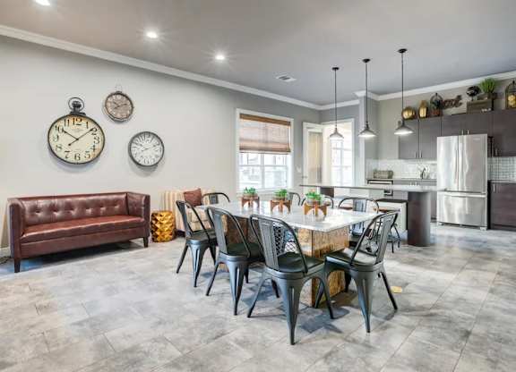 A modern dining room with a brown leather couch, a dining table set with plates, and three wall clocksat Century Ariva, Lakeland Florida  .