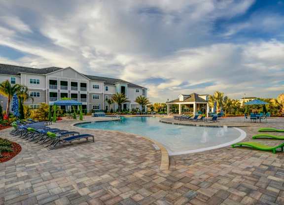 A large outdoor swimming pool surrounded by a brick patio and lounge chairs.at Century Ariva, Lakeland, 33812