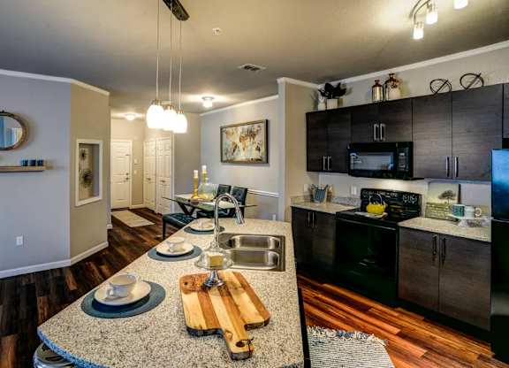 A kitchen with a granite countertop and a wooden cutting board at Century Ariva, Florida  .