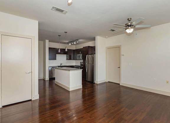 A kitchen with a refrigerator, sink, and stove is visible from the living room.at Century Cedar Hill, Texas, 75104