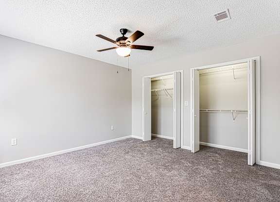 Empty bedroom with dual closets and ceiling fan at Salem Glen Apartments, Conyers, GA