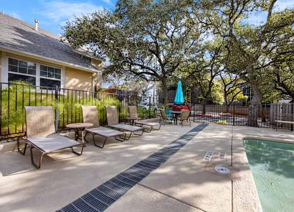 A pool area with a hot tub and lounge chairs.