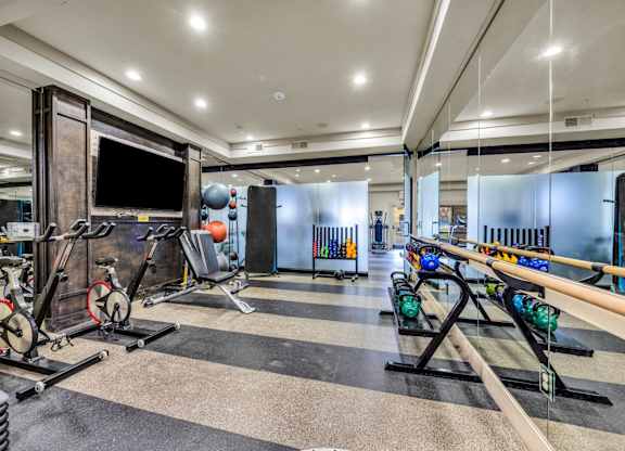 A gym with a variety of equipment including treadmills, weights, and exercise machines.