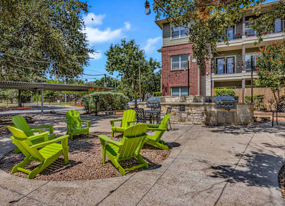 A park with green chairs and a building in the background.